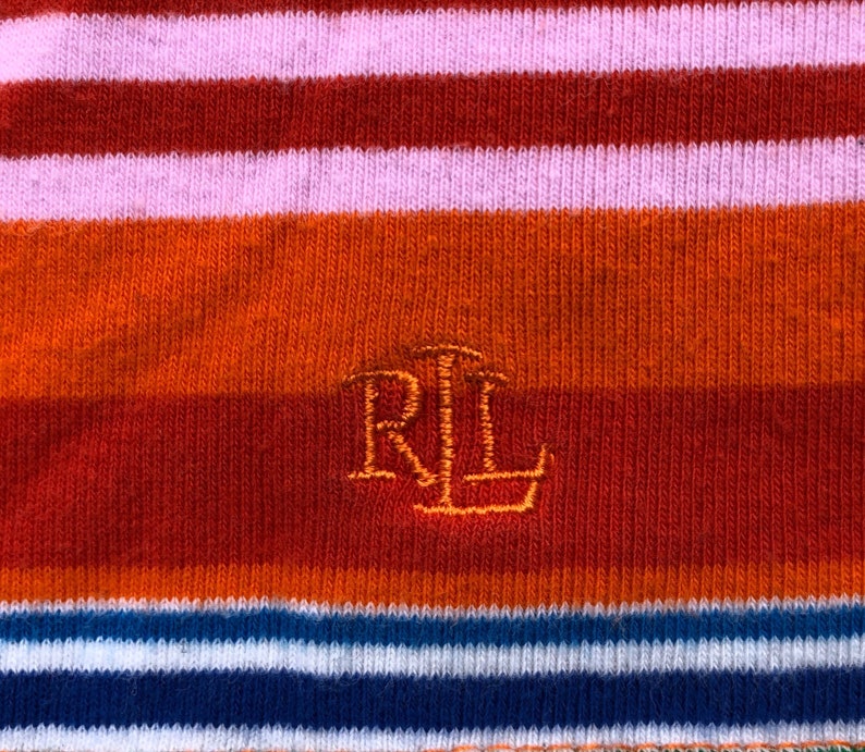 Peut inclure: Un gros plan sur un tissu ray&eacute; avec les lettres "RL" brod&eacute;es en fil orange.