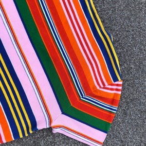 Peut inclure: Un gros plan sur un tissu ray&eacute; color&eacute; avec des rayures roses, orange, rouges, vertes, bleues et jaunes. Le tissu est pli&eacute; en deux et les rayures sont diagonales.