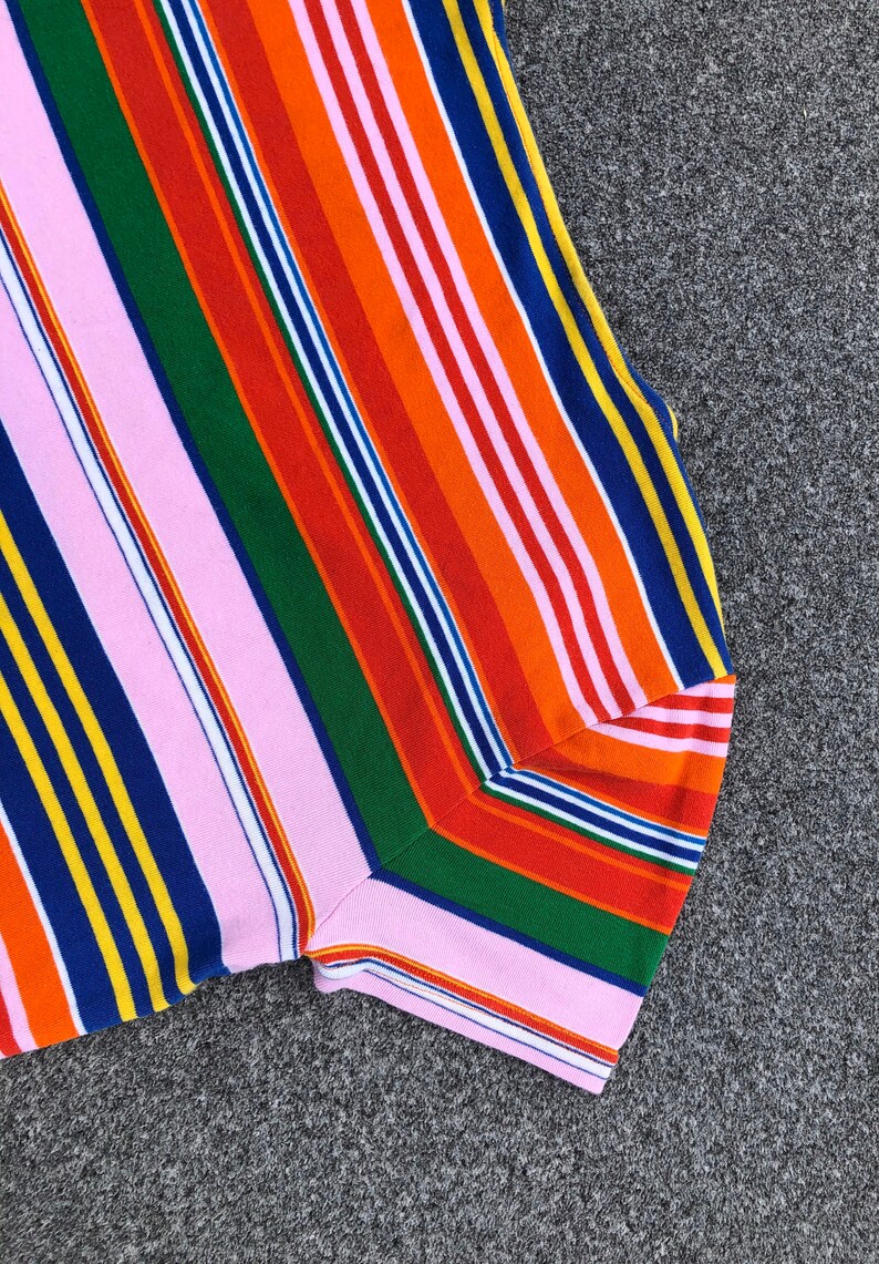 Peut inclure: Un gros plan sur un tissu ray&eacute; color&eacute; avec des rayures roses, orange, rouges, vertes, bleues et jaunes. Le tissu est pli&eacute; en deux et les rayures sont diagonales.