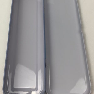 May include: A gray metal pencil case with a smooth, shiny finish. The case is open and empty.