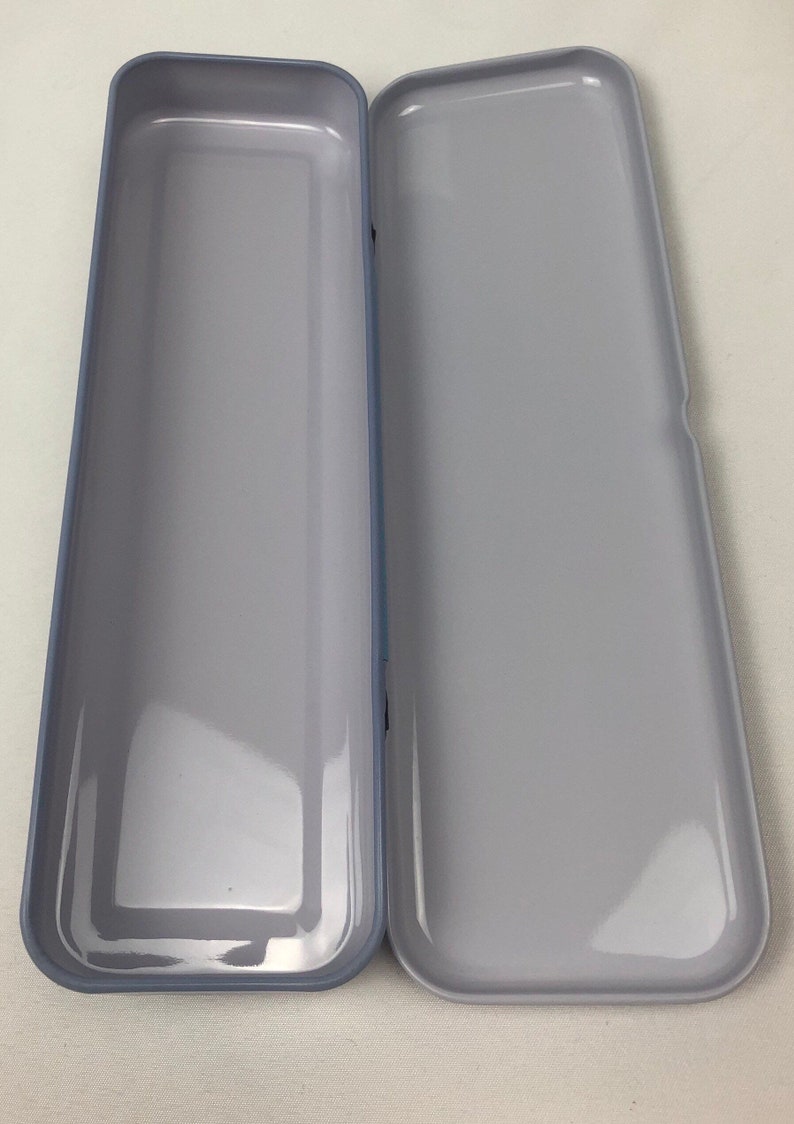 May include: A gray metal pencil case with a smooth, shiny finish. The case is open and empty.