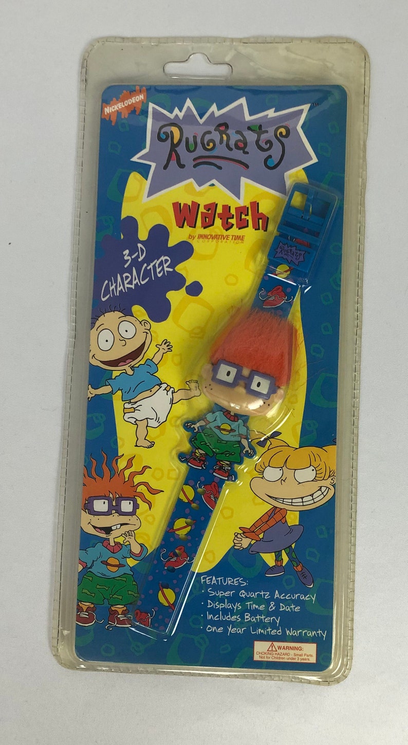 May include: A blue and yellow plastic package with a Nickelodeon Rugrats watch featuring a 3-D character. The watch has a blue band with a space-themed design and a 3-D character of Chuckie Finster with orange hair and glasses. The package features the text "Rugrats Watch" and "3-D Character".