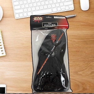 Puede incluir: Una caja de lápices de hojalata de Star Wars Episodio I con Darth Maul. La caja de lápices es negra con un diseño de Darth Maul rojo y negro. El embalaje incluye el texto "TIN PENCIL BOX".