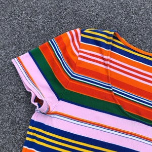 Peut inclure: Un t-shirt ray&eacute; rose, orange, bleu, vert et jaune avec un col rond.