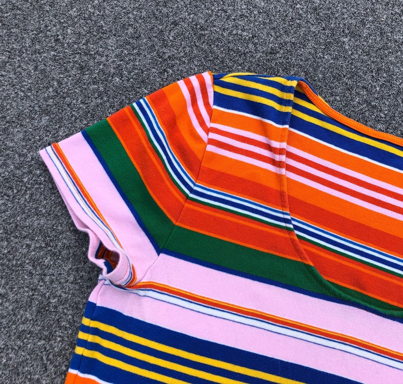 Peut inclure: Un t-shirt ray&eacute; rose, orange, bleu, vert et jaune avec un col rond.