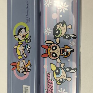 May include: A purple pencil case with a striped design and images of the Powerpuff Girls. The text "The Powerpuff Girls" is printed on the case. The back of the case has images of the Powerpuff Girls and the text "TM & Cartoon Network (s01)".