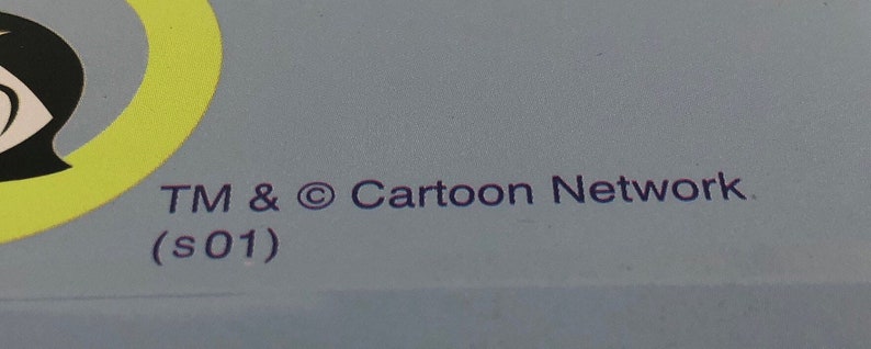 May include: A blue background with a yellow circle and a black and white cartoon character. The text "TM & &copy; Cartoon Network (s01)" is printed in purple.