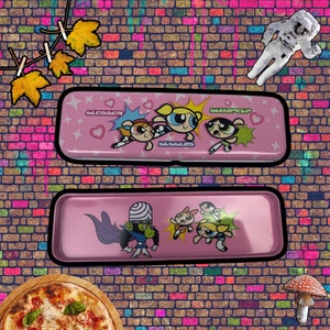 May include: Pink metal pencil case featuring the Powerpuff Girls characters Blossom, Bubbles, and Buttercup. The case also includes a graphic of Mojo Jojo, the girls' nemesis.