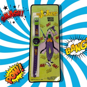 K&ouml;nnte beinhalten: Eine gr&uuml;n-violette Digitaluhr mit einem Bild des Jokers aus den Batman-Comics auf der Verpackung. Die Verpackung tr&auml;gt den Text "The Joker Digital Watch" und "Ha!" wird mehrmals wiederholt.