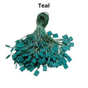 May include: Teal colored string with plastic tags attached. The string is twisted and the tags are piled on top of each other.