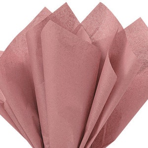 May include: A bundle of soft, pink tissue paper. The paper is folded in a fan shape, with the edges of the paper visible.