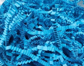 May include: A close-up of blue shredded paper, commonly used as packing material or for gift wrapping.