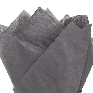 May include: A bundle of folded, charcoal-colored tissue paper. The tissue paper is arranged in a fan-like shape, with multiple layers visible. The paper has a slightly textured appearance and a matte finish, suitable for gift wrapping or crafting.