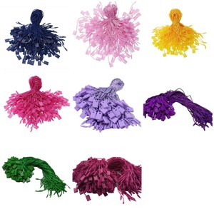 May include: Assortment of colorful string tags with plastic tips. The tags are in various colors, including blue, pink, purple, yellow, green, and red. The tags are bundled together and ready to be used for labeling or attaching to items.