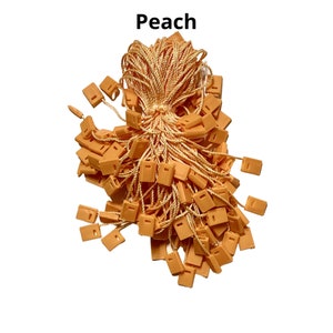 May include: A large bunch of peach-colored string tags with plastic loops. The tags are tied together with a long piece of string.