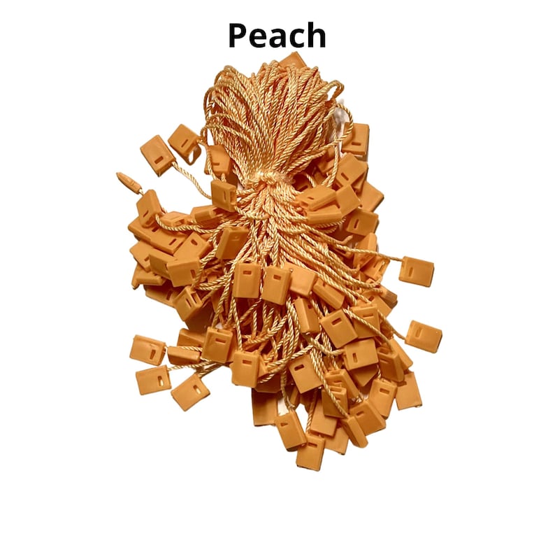 May include: A large bunch of peach-colored string tags with plastic loops. The tags are tied together with a long piece of string.