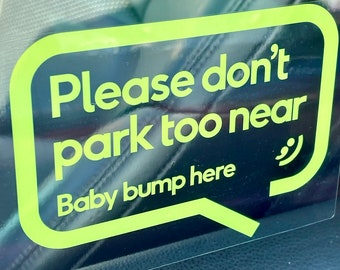 May include: A yellow and black sign with the text "Please don't park too near Baby bump here" and a smiley face.