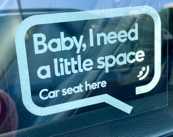 May include: White sticker on a car window with the text "Baby, I need a little space" and "Car seat here" in a speech bubble.