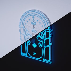 Può includere: Un'opera d'arte murale decorativa blu brillante con una parte superiore ad arco e disegni intricati. L'opera presenta una corona ed elementi floreali, con testo attorno al bordo superiore. Il pezzo è illuminato su uno sfondo scuro.