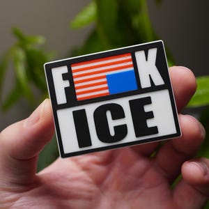 Może przedstawiać: Prostokątna naklejka z czarną obw&oacute;dką i słowami "F*CK ICE" pogrubioną, białą i czarną czcionką. "F" i "K" znajdują się nad "ICE". "F" i "K" znajdują się nad wzorem przypominającym flagę amerykańską. Słowo "MEDIUM" znajduje się w prawym dolnym rogu.