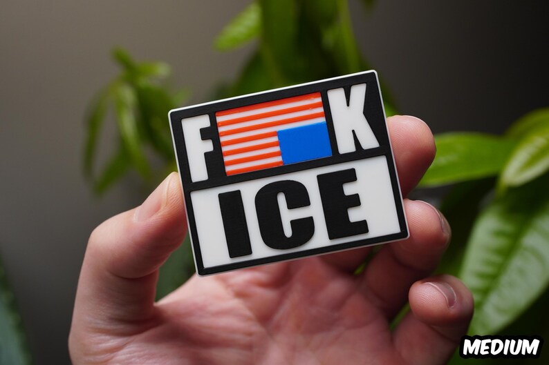 Może przedstawiać: Prostokątna naklejka z czarną obw&oacute;dką i słowami "F*CK ICE" pogrubioną, białą i czarną czcionką. "F" i "K" znajdują się nad "ICE". "F" i "K" znajdują się nad wzorem przypominającym flagę amerykańską. Słowo "MEDIUM" znajduje się w prawym dolnym rogu.