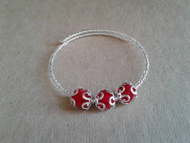 May include: A silver bracelet with three red beads. The beads have a silver filigree design.