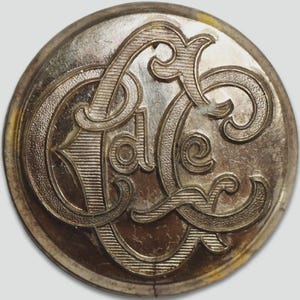 May include: A silver-toned button with the letters "C.C." in a decorative script.