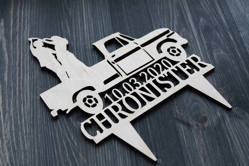 May include: Wooden cake topper featuring a silhouette of a couple standing in the back of a pickup truck. The truck has the date "10.03.2020" and the name "CHRONISTER" written on the side.
