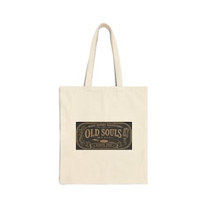 May include: A beige canvas tote bag featuring a rectangular black graphic with gold text that reads "OLD SOULS MUSIC" and "MUSIC BEFORE ALGORITHMS SINCE 1957." The design includes a vintage microphone and a vinyl record illustration with ornate borders.