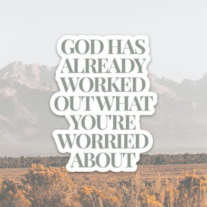 May include: A sticker with the text "GOD HAS ALREADY WORKED OUT WHAT YOU'RE WORRIED ABOUT" in a white, stylized font. The background features a blurred landscape with mountains, fields, and a muted color palette.