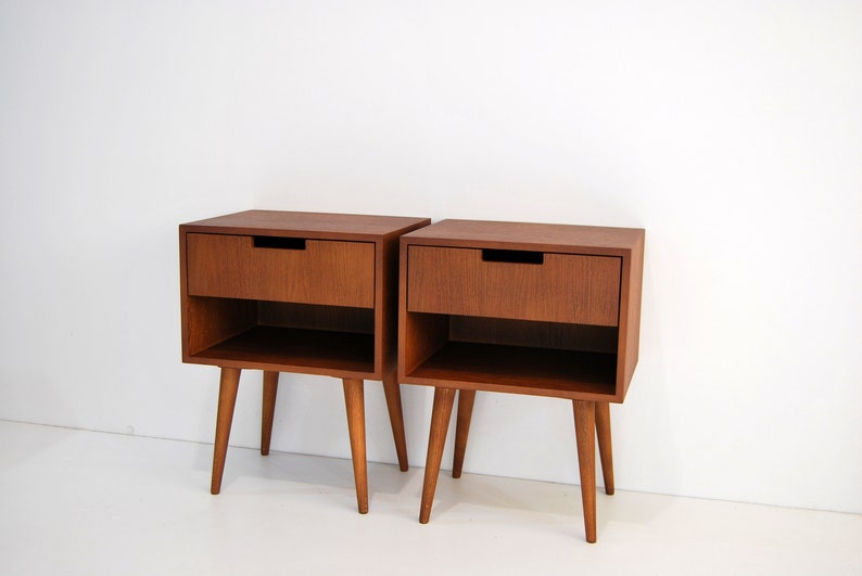 May include: Two wooden bedside tables with drawers and shelves. The tables are brown and have four legs.