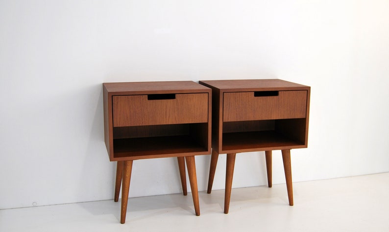May include: Two wooden nightstands with a single drawer and a lower shelf. Each nightstand has four tapered legs.