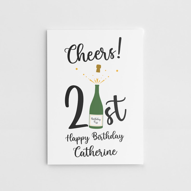 Puede incluir: Una tarjeta blanca con texto negro que dice "Cheers! 21st Happy Birthday Catherine". Hay una botella de champ&aacute;n verde con un corcho dorado que sale de la parte superior del n&uacute;mero 21.