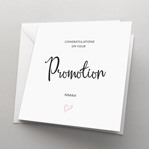 May include: White card with black text that reads "Congratulations on your Promotion" and "Nimah". A pink heart is drawn below the text.