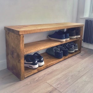 May include: A rustic wooden shoe rack with two shelves. The rack is made of reclaimed wood and has a natural finish. It's a great way to organise shoes and keep them off the floor.