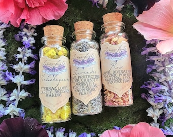 Könnte beinhalten: Drei kleine Glasflaschen gefüllt mit getrockneten Kräutern und Blumen. Jede Flasche hat ein Etikett mit dem Namen des Krauts und seinen zugehörigen Eigenschaften. Die Etiketten lauten "Helichrysum", "Lavendel" und "Rose".