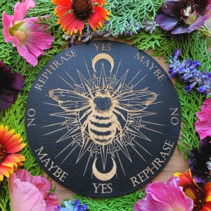 May include: Black wooden circular board with a gold bee design and the words "Yes", "Maybe", "No", and "Rephrase" around the edge.