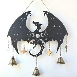 May include: Black metal dragon wind chime with gold stars, moons, and keys hanging from chains. The dragon is silhouetted against a starry sky.