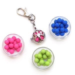 Peut inclure: Un charme argenté avec une cage en métal contenant des perles roses, un charme argenté avec une cage en métal contenant des perles vertes et un charme argenté avec une cage en métal contenant des perles bleues. Les charmes sont attachés à un porte-clés argenté.