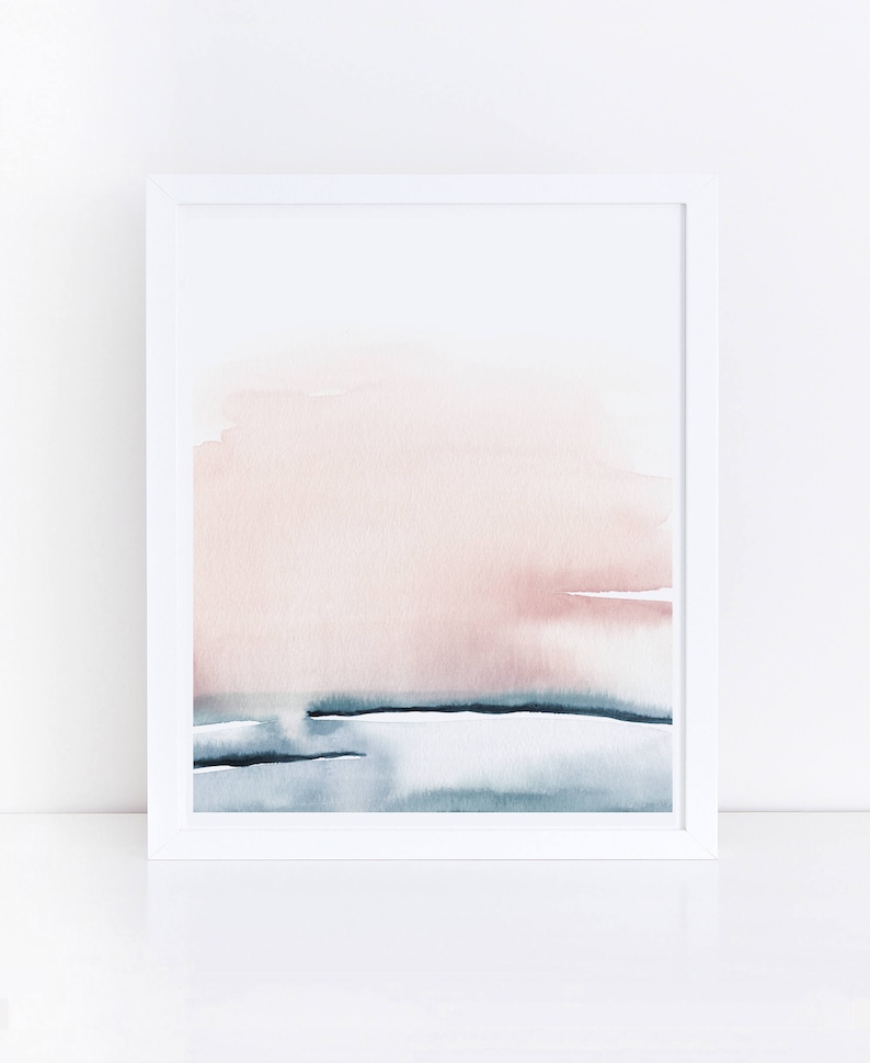 May include: Abstract watercolor painting in a white frame. The painting features a soft pink and blue color scheme with a horizontal line separating the two colors.