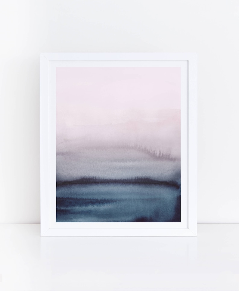 May include: Abstract watercolour painting in a white frame. The painting features a gradient of pink, purple, and blue colours, creating a hazy, atmospheric effect.