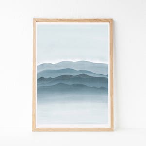 May include: A framed print of a watercolor painting depicting a blue and gray mountain range with a hazy, misty background.