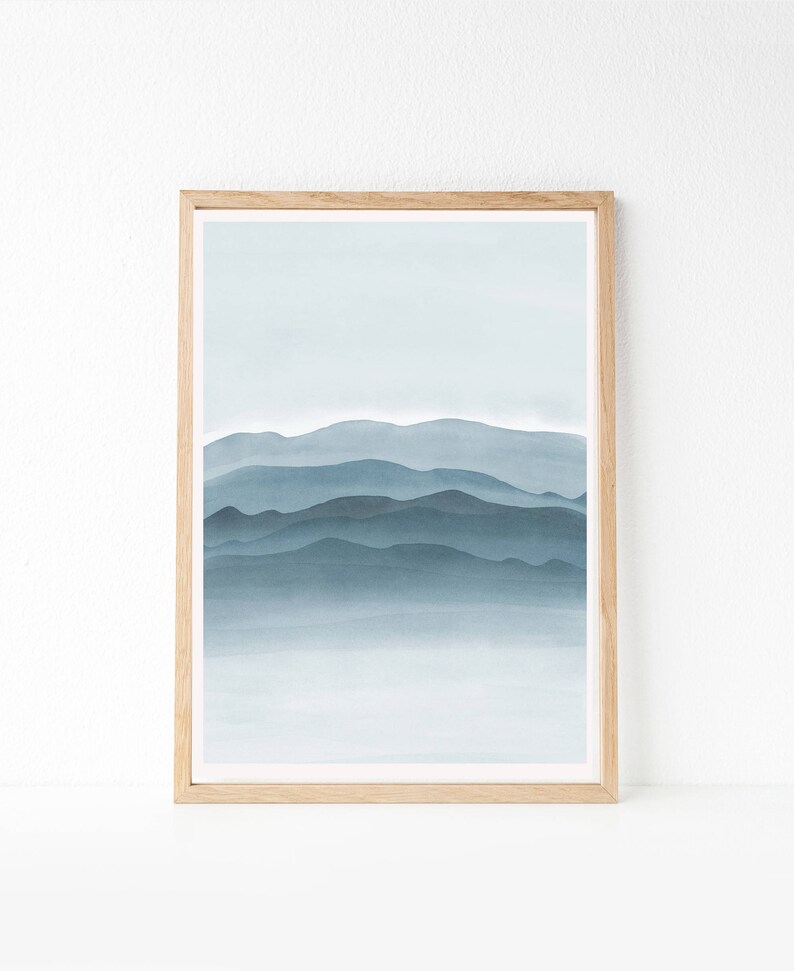 May include: A framed print of a watercolor painting depicting a blue and gray mountain range with a hazy, misty background.