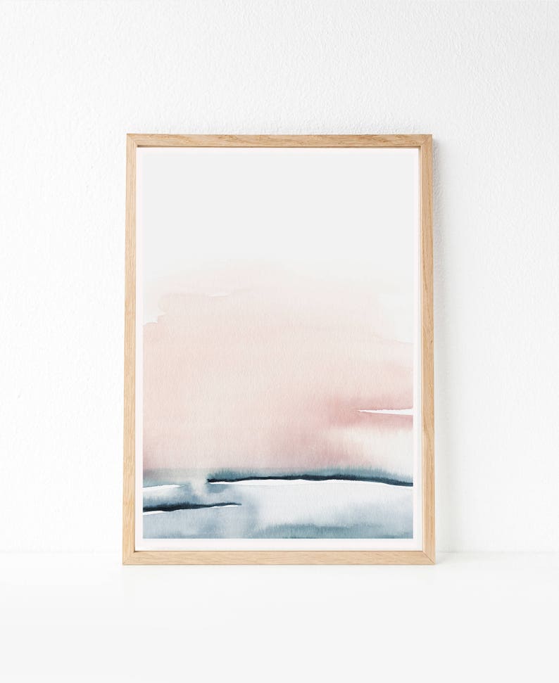 May include: A framed abstract watercolor painting with a pink and blue color scheme. The painting features a soft, blended transition from a light pink to a darker blue, creating a sense of depth and movement. The painting is framed in a simple, natural wood frame.