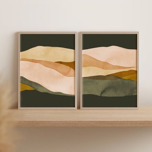 May include: Two framed abstract landscape paintings with a muted color palette of beige, brown, and green. The paintings are in a modern style and feature a layered, abstract design.