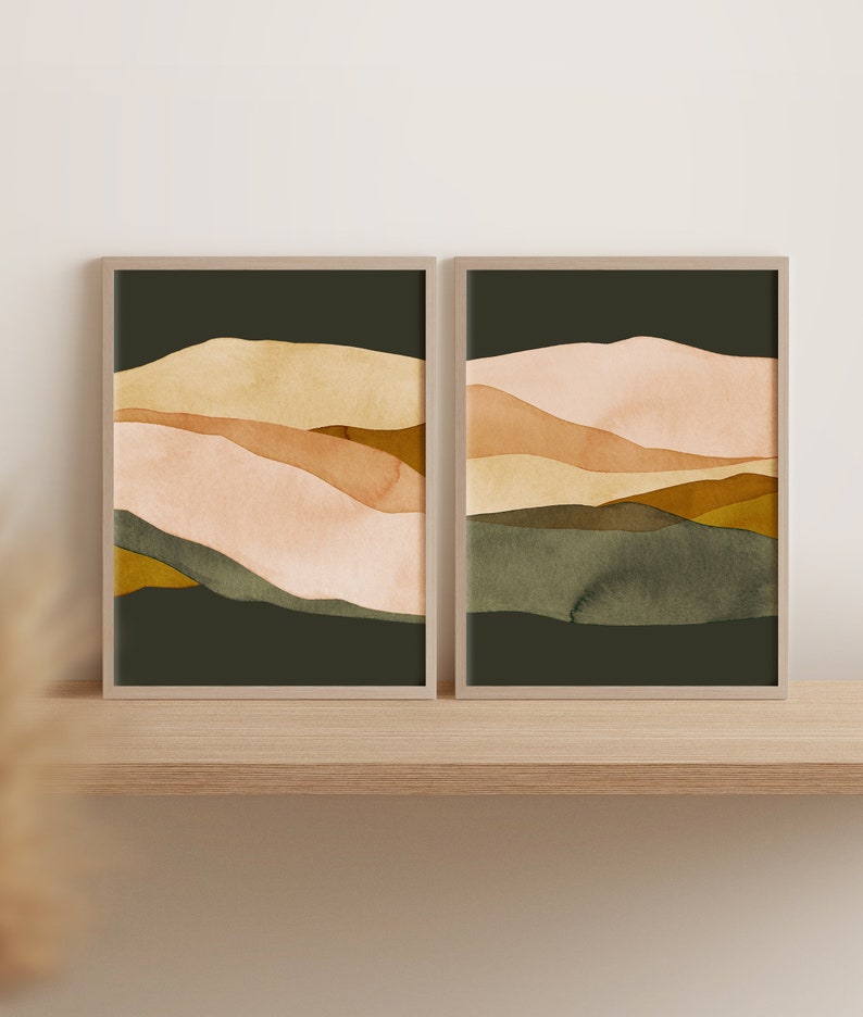 May include: Two framed abstract landscape paintings with a muted color palette of beige, brown, and green. The paintings are in a modern style and feature a layered, abstract design.