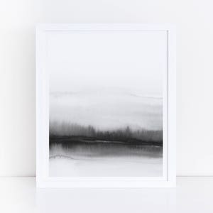 May include: A black and white abstract watercolor painting in a white frame. The painting depicts a landscape with a horizon line and a dark, cloudy sky.