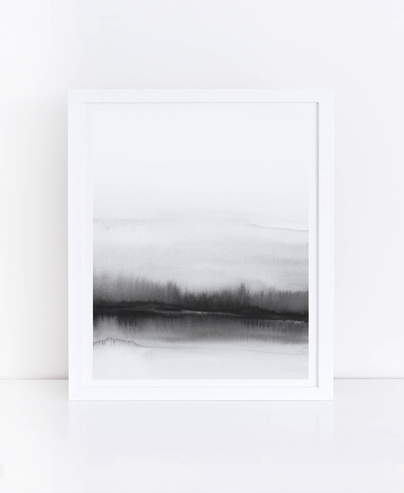 May include: A black and white abstract watercolor painting in a white frame. The painting depicts a landscape with a horizon line and a dark, cloudy sky.