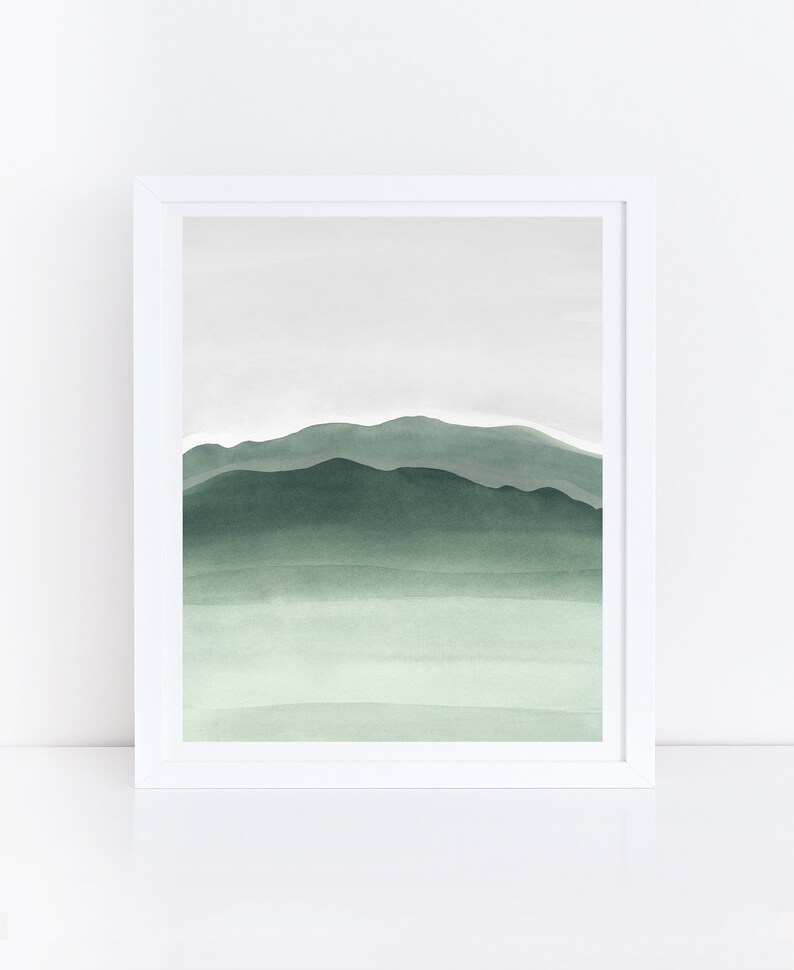 May include: A framed watercolor painting of a green mountain range with a light green sky. The painting is in a white frame.