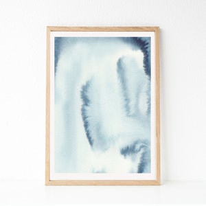 May include: A framed abstract watercolour painting with shades of blue and white. The painting has a soft, ethereal feel and is perfect for adding a touch of modern art to any room.
